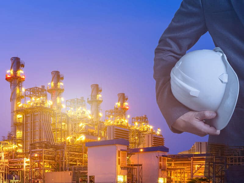 Closeup of executive with hard hat in front of power plant at dusk