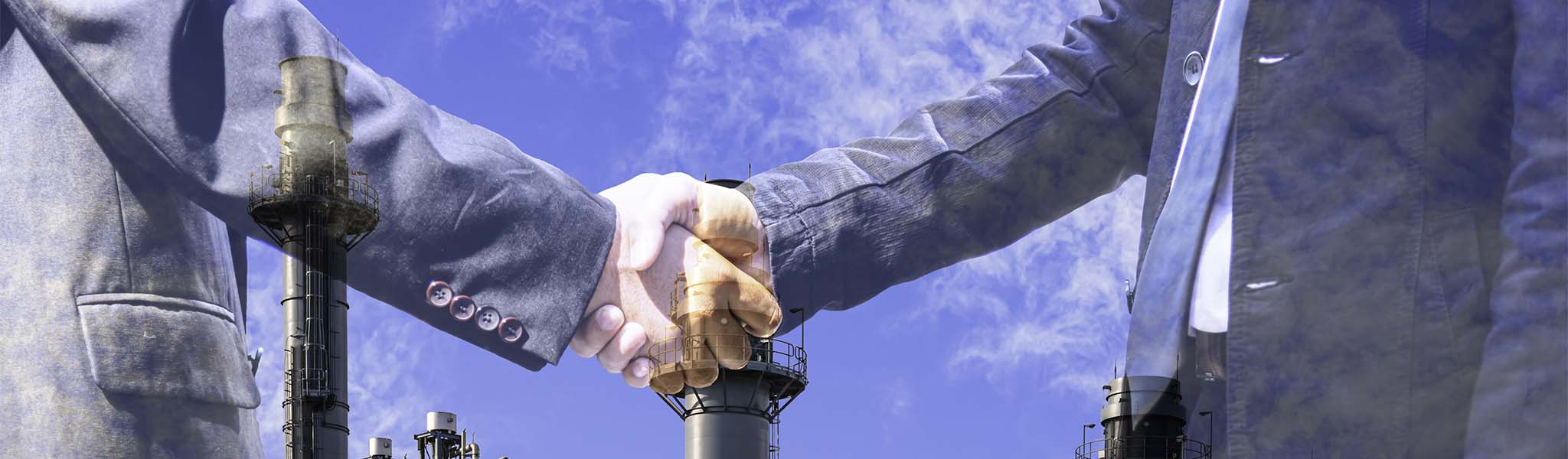 Closeup of two businessmen shaking hands overlaid on photo of power plant